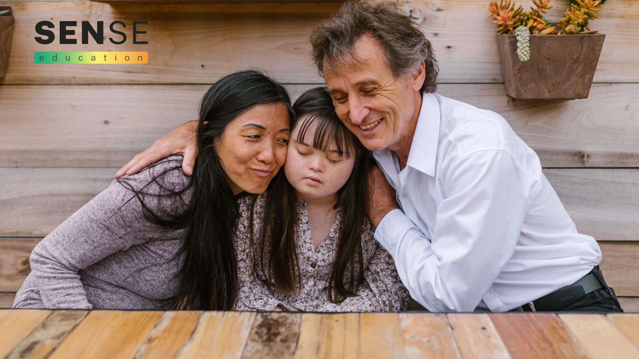 Two adults supporting a young person with downs syndrome