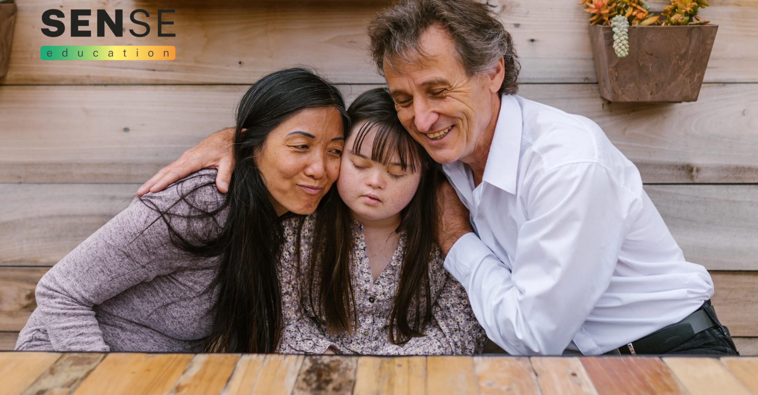 Two adults supporting a young person with downs syndrome